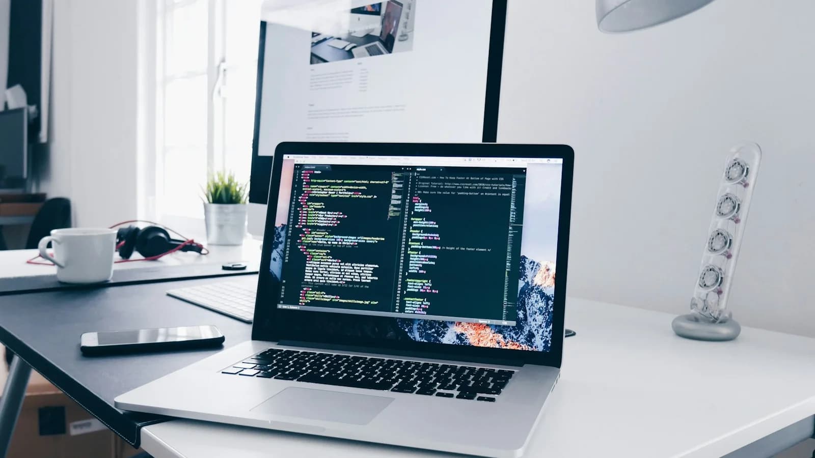 A developer workstation with dual monitors displaying code editor, terminal, and testing environment